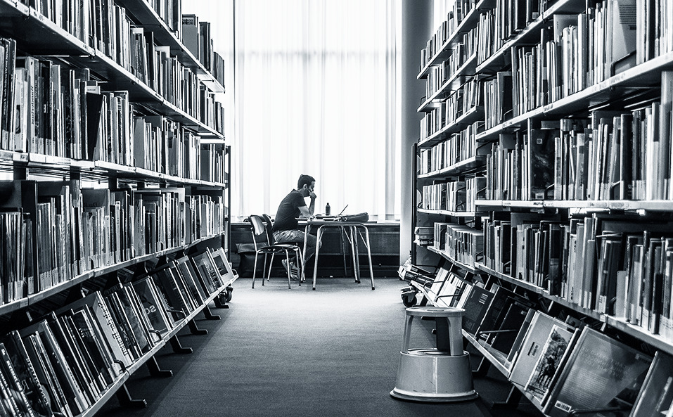 man reading a lot of books in the library
