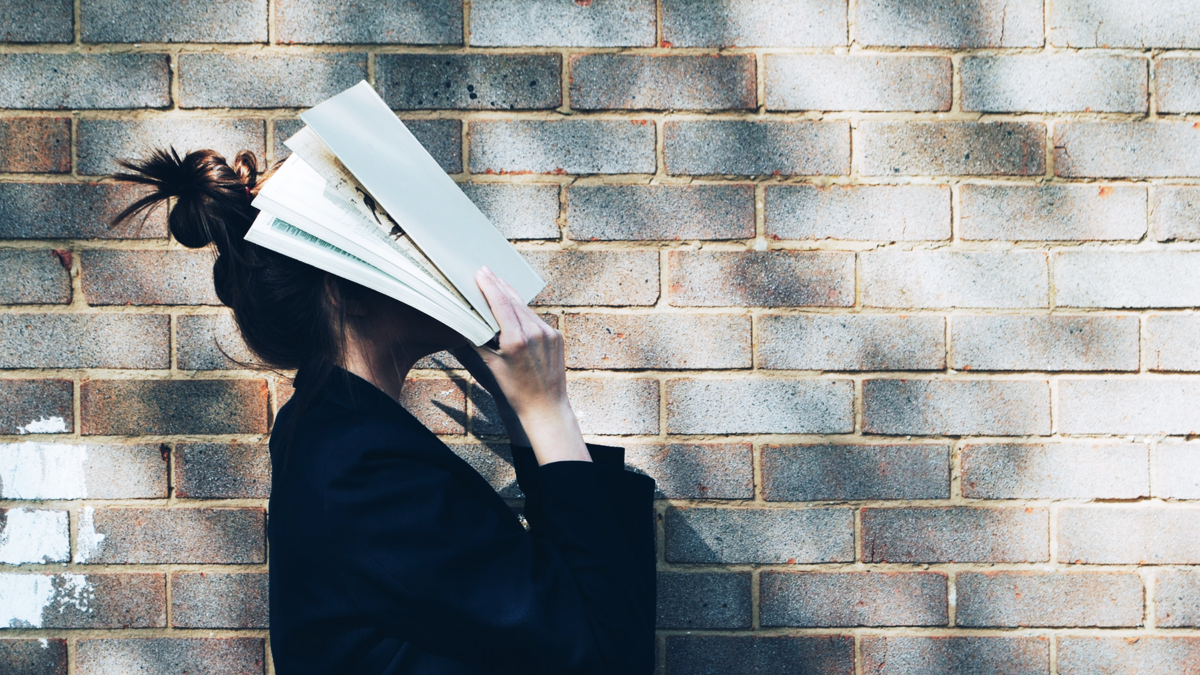 woman hiding her face with a book